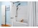 Bright bathroom features a tub with shower, a blue accent wall, and gold fixtures at 8834 Palmetto Rd, Edisto Island, SC 29438