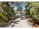 Long gravel driveway leading to a charming home surrounded by mature trees and lush foliage at 8834 Palmetto Rd, Edisto Island, SC 29438