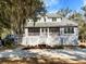 Two-story home featuring a large porch and landscaped front yard on a sunny day at 8834 Palmetto Rd, Edisto Island, SC 29438