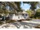 Charming home with a screened porch, gray siding, white trim, and a circular driveway surrounded by trees at 8834 Palmetto Rd, Edisto Island, SC 29438