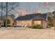Expansive backyard with brick home exterior, covered porch, patio, and sunset sky at 1006 Retreat Ave, Moncks Corner, SC 29461