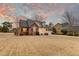 Charming brick home with manicured lawn and mature trees under a colorful sky at dusk at 1006 Retreat Ave, Moncks Corner, SC 29461