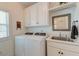 Well-lit laundry room featuring modern appliances, cabinetry, sink, mirror, and window at 1006 Retreat Ave, Moncks Corner, SC 29461
