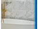 Close up of modern bathtub with gold fixtures and marble tile walls at 111 S Battery St, Charleston, SC 29401