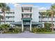 Inviting condo building entrance with palm trees, manicured landscaping and covered entryway at 166 W Mariners Cay Dr, Folly Beach, SC 29439