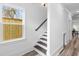 Hallway staircase with decorative window, wooden steps, white walls, and wood-style flooring at 2008 Emden St, North Charleston, SC 29406