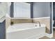 Well lit bathroom featuring a soaking tub with tile accents, a window with blinds, and gray painted walls at 231 Laurel Crest Way, Summerville, SC 29486