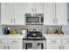 Close-up of a modern kitchen with white countertops, stainless steel appliances, and decorative backsplash at 231 Laurel Crest Way, Summerville, SC 29486