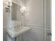 Elegant powder room with classic white fixtures, wainscoting, and stylish sconces at 2972 Riverwood Dr, Mount Pleasant, SC 29466