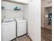 Well-lit laundry room features modern appliances and storage shelf for convenient home care at 305 Flowering Peach Ct # 202, Charleston, SC 29414