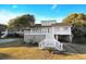 A charming white house with a spacious front yard, mature trees, and elevated design at 707 Palmetto Blvd, Edisto Island, SC 29438