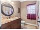 This bathroom features a round mirror over a granite sink and unique red curtains at 8209 Governors Walk, North Charleston, SC 29418