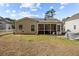 Picture of the rear of a house with a large screened in porch, a fenced backyard, and a stone patio at 9021 Robins Nest Way, Summerville, SC 29485