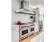 Close-up of a gourmet kitchen featuring stainless steel appliances and a large stove and custom range hood at 146 S Battery St, Charleston, SC 29401