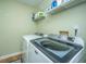 Bright laundry room featuring a white washer and dryer and storage shelving above with cleaning supplies at 1466 Arrow Wind Ter, Charleston, SC 29414