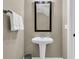 Compact powder room featuring a pedestal sink, modern faucet, and rectangular framed mirror at 1992 Pierce St, Charleston, SC 29492