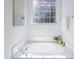 Bright and sunny white bathtub with chrome hardware, located near a gridded window at 2128 Baldwin Park Dr, Mount Pleasant, SC 29466