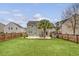 A large backyard with a manicured lawn, patio area, palm tree, and privacy fence at 222 Medford Dr, Summerville, SC 29485