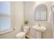 A half bathroom featuring a pedestal sink, arched mirror, toilet, and shuttered window at 222 Medford Dr, Summerville, SC 29485