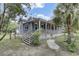 Quaint house features a wooden porch and stairs surrounded by lush green foliage and mature trees at 2530 Jasper Blvd, Sullivans Island, SC 29482