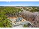 An aerial view captures a house with a detached garage surrounded by green trees and a body of water in the distance at 2725 Starfish Dr, Johns Island, SC 29455