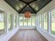 Sunroom features many windows, a statement light fixture, hardwood floors and vaulted ceilings at 3902 Summerton St, Mount Pleasant, SC 29466