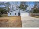 Charming blue home with an attached garage and driveway, surrounded by mature trees and an unfenced lawn at 4618 Moss Ct, Charleston, SC 29420