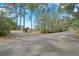 Paved driveway leading to a gated property, framed by mature trees and lush greenery at 4801 Coon Club Rd, Meggett, SC 29449