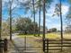 Charming property entrance with a black iron gate, long driveway, and mature trees framing the house at 4801 Coon Club Rd, Meggett, SC 29449
