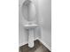 Stylish powder room showcasing a pedestal sink with a round mirror and dark hardwood flooring at 511 Verdi Dr, Summerville, SC 29486