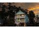 Lovely two-story coastal home with double porches is beautifully illuminated by golden hour sunset light at 520 Sanders Farm Ln, Wando, SC 29492