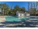A community pool features clear blue water and is surrounded by lush trees and other natural landscaping at 8120 Shadow Oak Dr, North Charleston, SC 29406