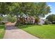 Traditional brick home featuring a lush lawn and mature shade trees creating a park-like setting at 904 Watermelon Run, Charleston, SC 29412
