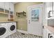 Well-organized laundry room with white cabinets, butcher block countertops, and stylish tiled floors at 904 Watermelon Run, Charleston, SC 29412