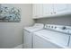 Laundry room with washer and dryer and custom cabinets, and a light gray wall with a bird themed painting at 1025 Riverland Woods Pl # 801, Charleston, SC 29412