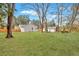 Spacious backyard with a large lawn, mature trees, a privacy fence, and outbuildings at 1744 Pinckney Park Dr, Charleston, SC 29407