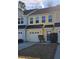 Charming yellow two-story townhouse with a garage, a black awning, and well-kept landscaping at 205 Grand Palm Ln, Summerville, SC 29485