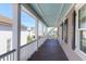 Spacious covered porch with wooden floors, white pillars, and a view of the neighborhood and blue sky at 23 Lowndes Pointe Dr, Charleston, SC 29403
