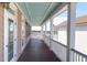 Inviting covered porch features a wooden floor, white railings, and views of the marsh, neighborhood, and blue sky at 23 Lowndes Pointe Dr, Charleston, SC 29403
