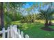 Picturesque backyard featuring a serene pond, framed by lush greenery, mature trees, and a white picket fence at 2690 Park W Blvd, Mount Pleasant, SC 29466