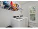 Bright laundry room featuring a modern washer and dryer, with shelving for storage and a window with wooden shutters at 2690 Park W Blvd, Mount Pleasant, SC 29466