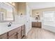 A bathroom features a double sink vanity, a tub, and wood-look flooring, perfect for relaxation at 301 Forsythia Ave, Summerville, SC 29483