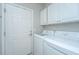 Well-equipped laundry room featuring white cabinets, a utility sink, and modern washer and dryer units at 303 Sand Dune Trl, Summerville, SC 29486