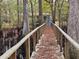 Wooden walkway with railings leading to a cottage, providing a charming entrance through the woods at 3695 Cannon Rd, Round O, SC 29474