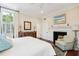 Comfortable bedroom showcasing a fireplace, seating area, hardwood floors, and natural light from the window at 41 Tradd St, Charleston, SC 29401