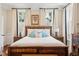 Well-lit bedroom with a rustic wood bed, two windows with shutters, and unique side tables at 41 Tradd St, Charleston, SC 29401