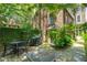 Inviting brick patio with outdoor dining set, perfect for relaxing or entertaining amidst lush greenery and mature trees at 41 Tradd St, Charleston, SC 29401