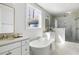 Luxurious bathroom featuring a soaking tub, a marble-tiled shower, and double vanity sinks with elegant fixtures at 5680 Barbary Coast Rd, Hollywood, SC 29449