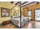 Spacious bedroom with yellow walls, exposed beams, and unique canopy bed on terra cotta tile flooring at 710 S Main St, Summerville, SC 29483
