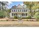Charming two-story home featuring a welcoming front porch, black shutters, mature trees and manicured lawn at 710 S Main St, Summerville, SC 29483